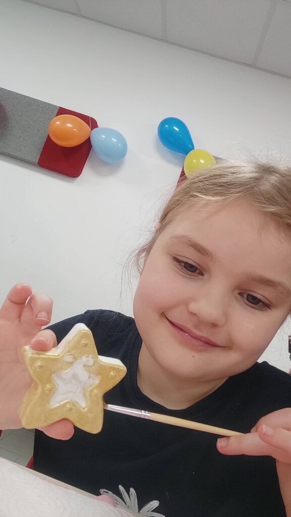 dziecko pokazuje pomalowaną figurkę gipsową na urodzinach